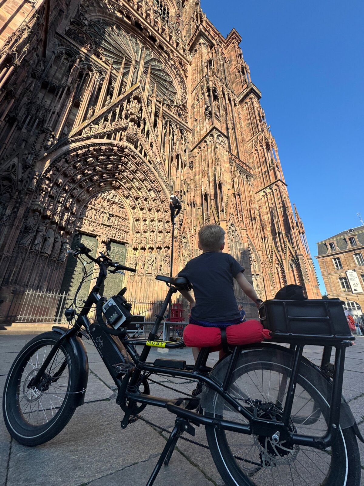 Child on a STRIM e-bike in front of Strasbourg Cathedral's Gothic façade
